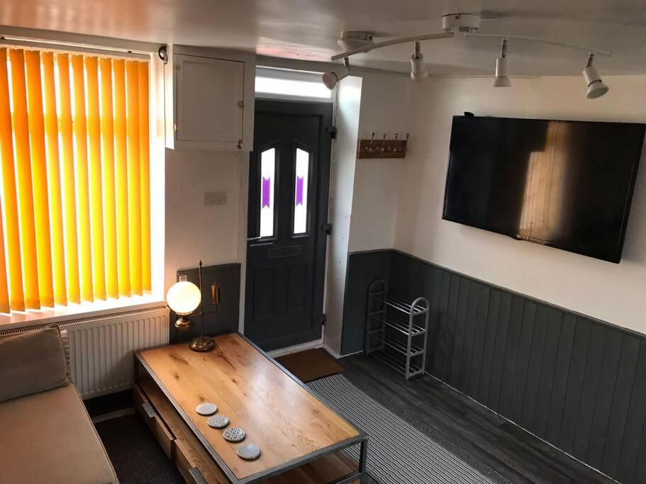 a living room with a wooden table and a tv at Bikers Grove Cottage in Troed-y-rhiw