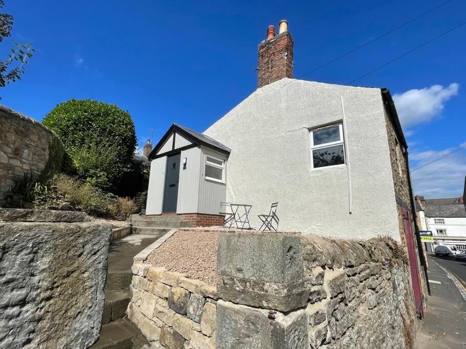 a small white house with a brick wall at Vine Cottage in Hexham