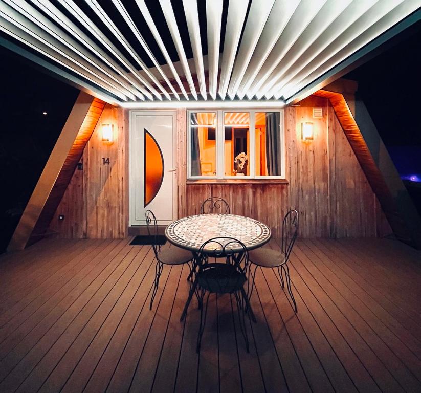 a table and chairs on a deck with a window at Au-Doux-Altic chalet romantique avec JACUZZI ET SAUNA in Métabief