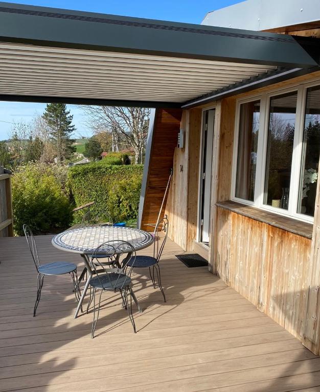 a patio with a table and chairs on a deck at Au-Doux-Altic chalet romantique avec JACUZZI ET SAUNA in Métabief