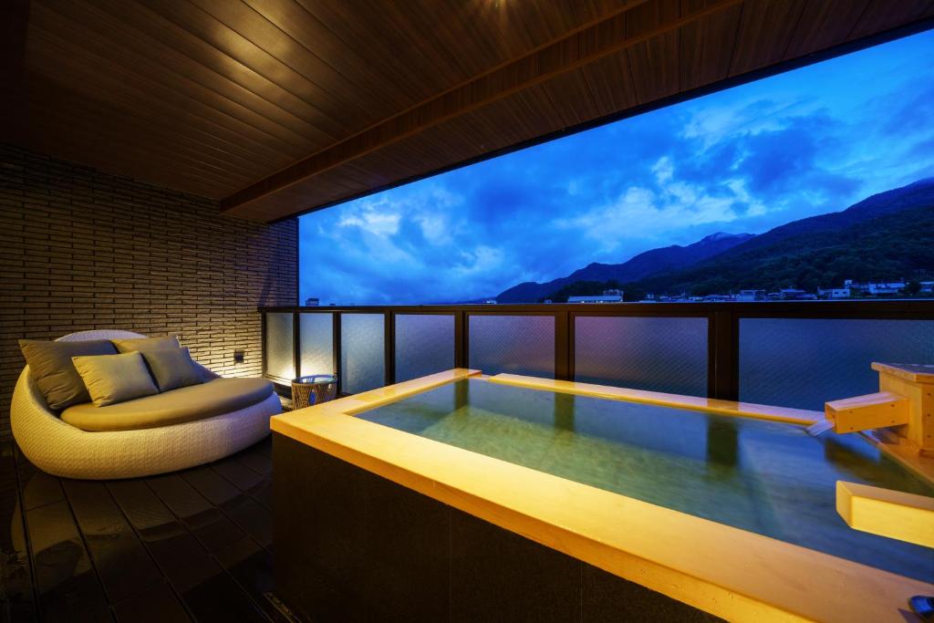 Zimmer mit Badewanne, Stuhl und TV in der Unterkunft Aburaya Tousen in Yamanouchi