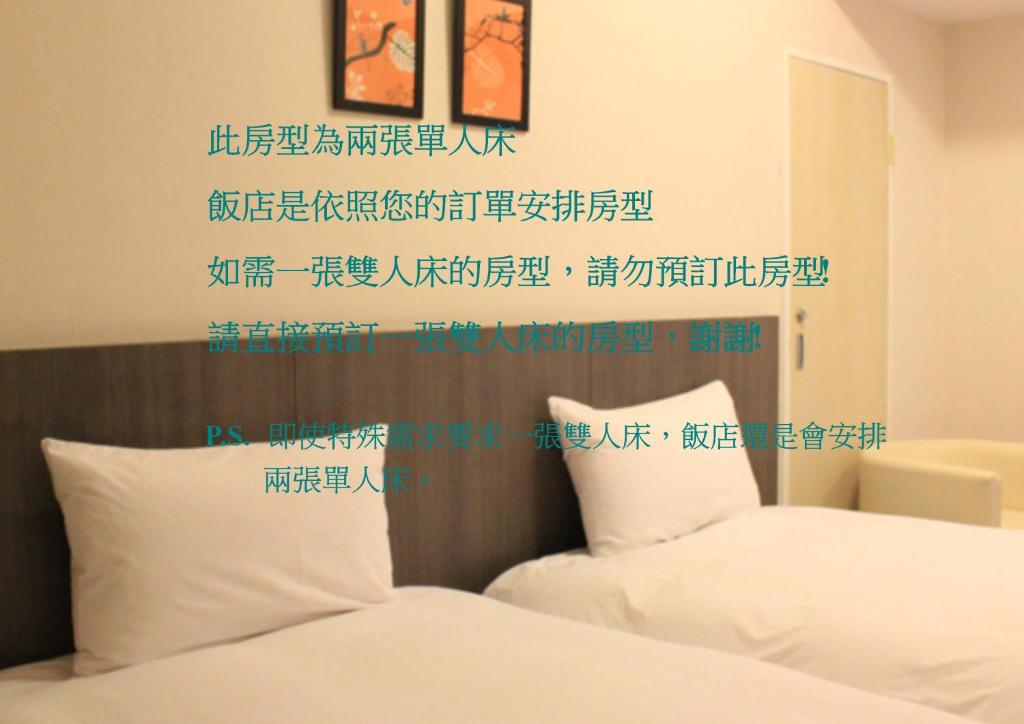 ein Schlafzimmer mit 2 Betten mit chinesischem Schreiben an der Wand in der Unterkunft Sunnyside Hotel in Kaohsiung