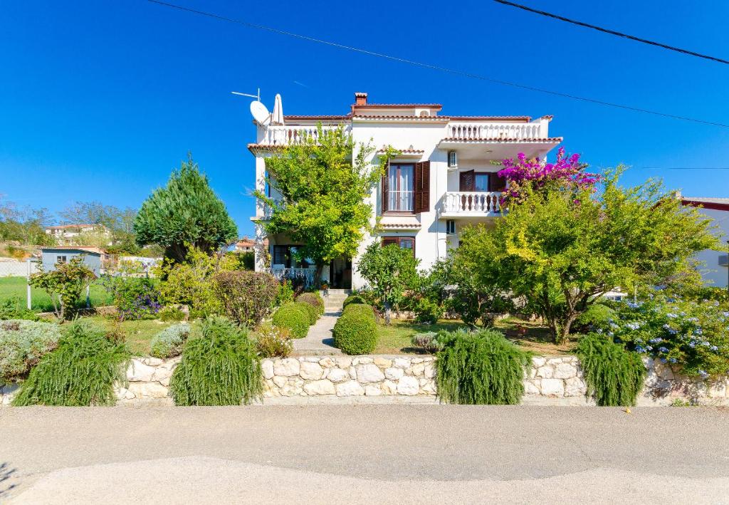 une grande maison blanche avec des arbres et des buissons dans l'établissement Apartments Ljubica J, à Lopar