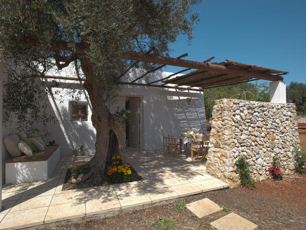 a patio with a tree and a stone wall at I Mulicchi in Specchia