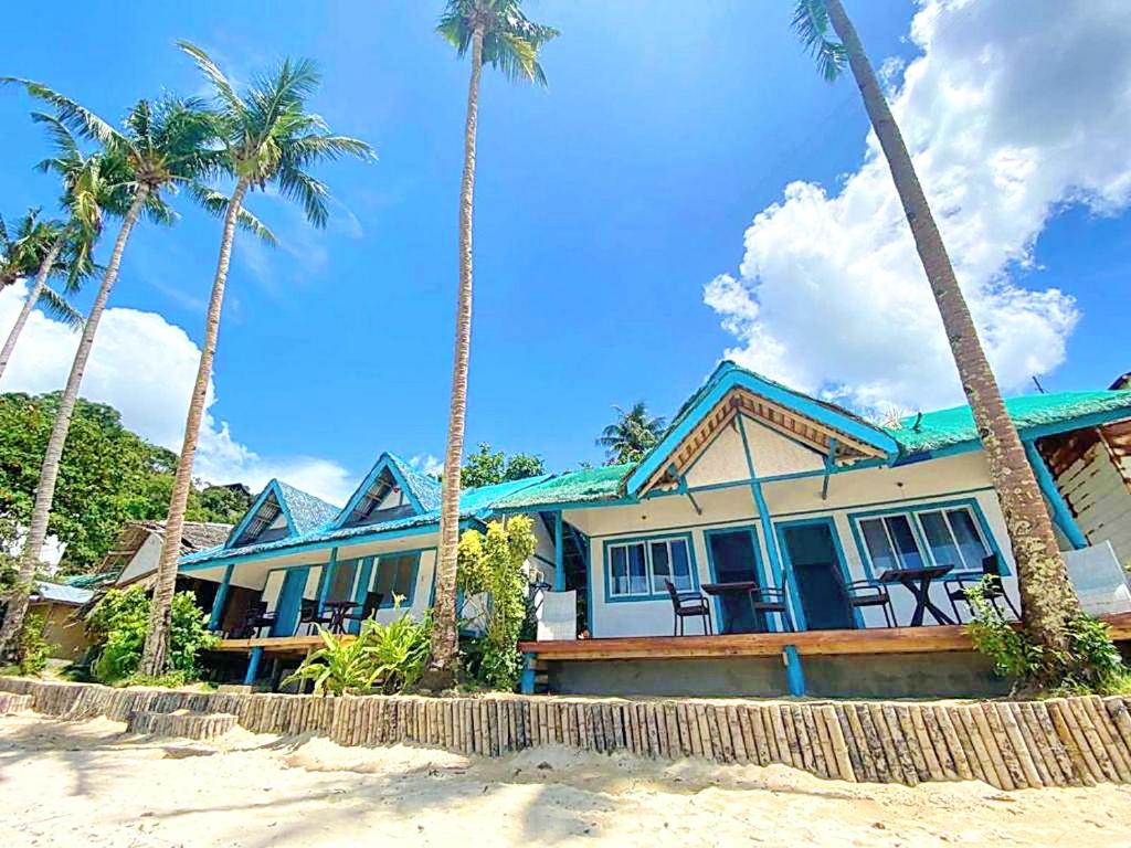 a house on the beach with palm trees at Beach Huts El Nido in El Nido