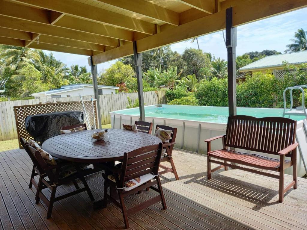 a wooden deck with a table and chairs and a pool at Eve and Sandys Holiday Home in Rarotonga