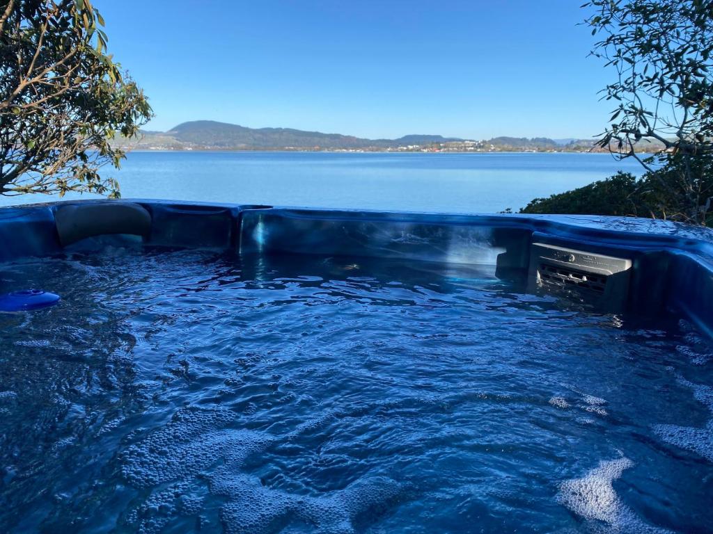 uma banheira de hidromassagem com vista para a água em The Willows em Rotorua