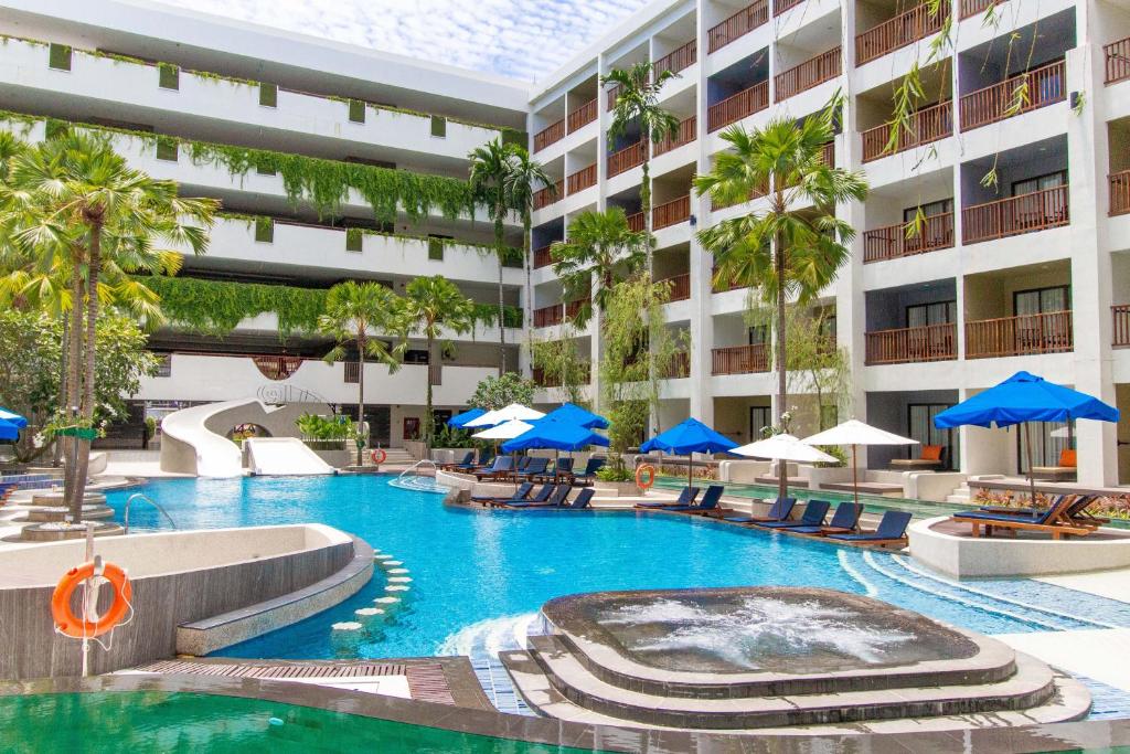 a swimming pool with chairs and umbrellas in a hotel at Deevana Plaza Phuket - SHA Extra Plus in Patong Beach