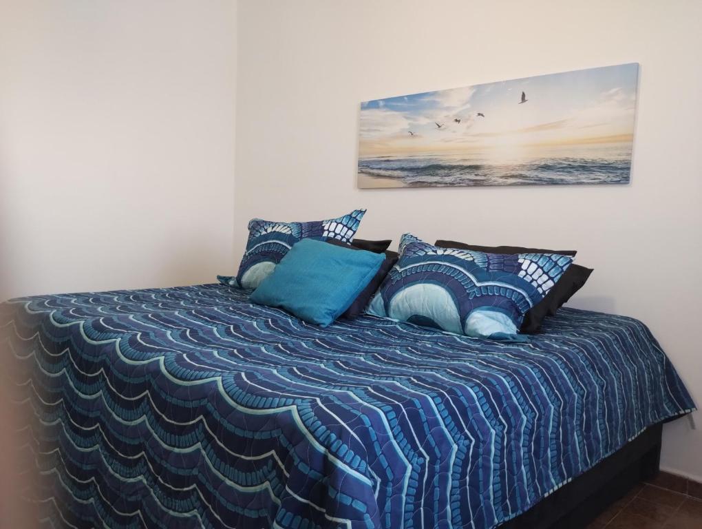 um quarto com uma cama com um edredão azul em Apto da Li na Praia Grande I na Praia Grande