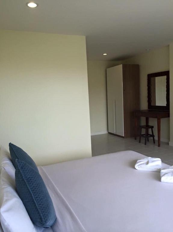 a bedroom with a bed with blue pillows and a table at Glitter House in Phuket