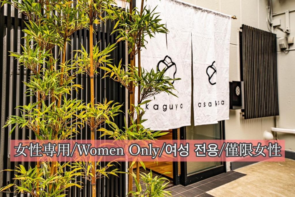 un panneau devant un bâtiment avec des plantes dans l'établissement kaguya asakusa Women only guest house, à Tokyo