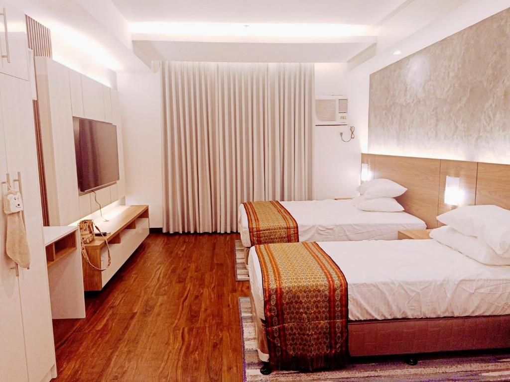 a hotel room with two beds and a television at Cozy Suite Studio type condo in Matina Enclaves in Davao City