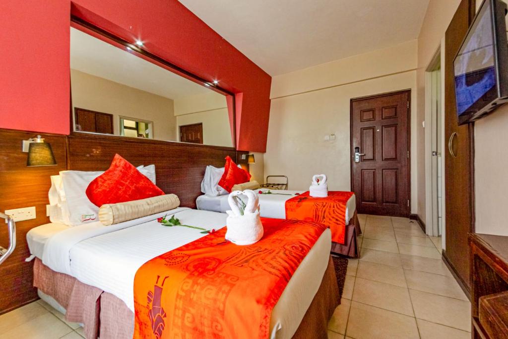 a hotel room with two beds and a mirror at Hotel Rio in Nairobi