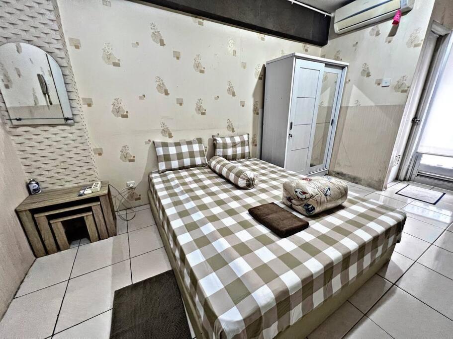 - une chambre avec un lit et une couverture en damier dans l'établissement Comfy Studio with Smart Tv&Fast Wifi @Baywalk Mall, à Jakarta