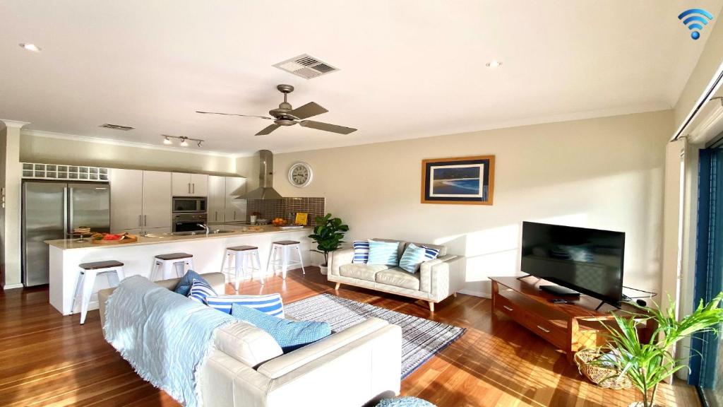 a living room with a couch and a kitchen at Blueys Lodge in Anna Bay