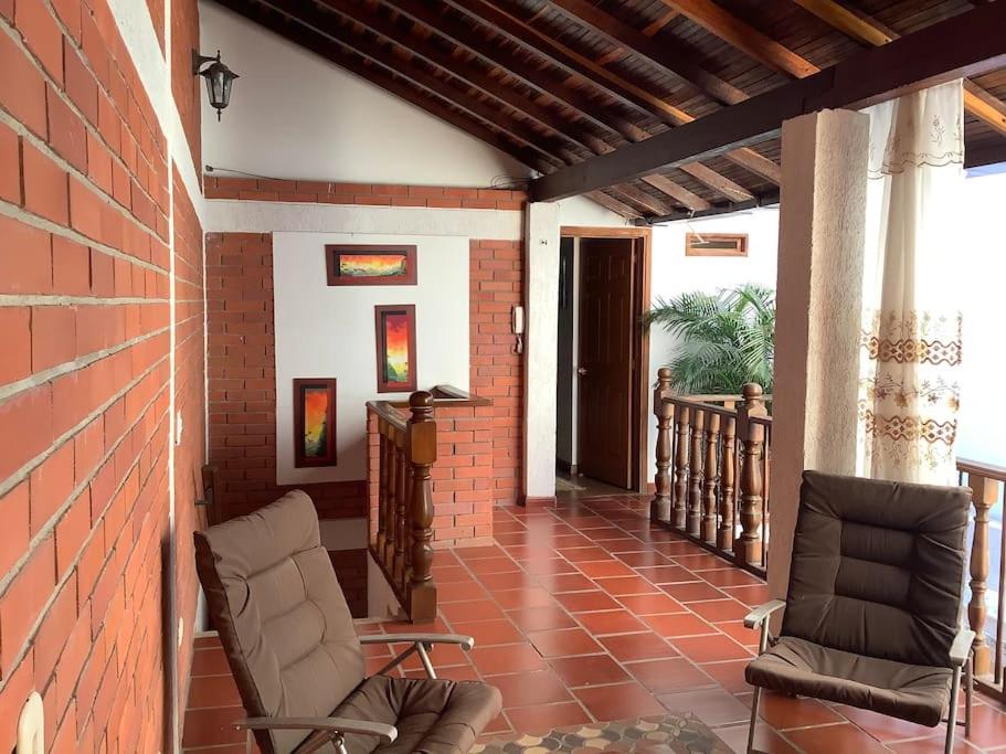 un porche con 2 sillas y una pared de ladrillo en San Gil beautiful house en San Gil