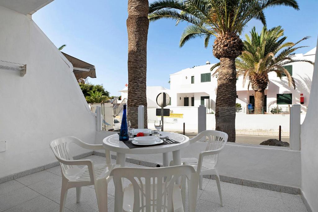 a white table and chairs on a balcony with palm trees at Ianoa in Tías