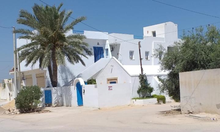 a white building with a palm tree in front of it at Dar Janis Djerba دار يانيس جربة in Houmt Souk