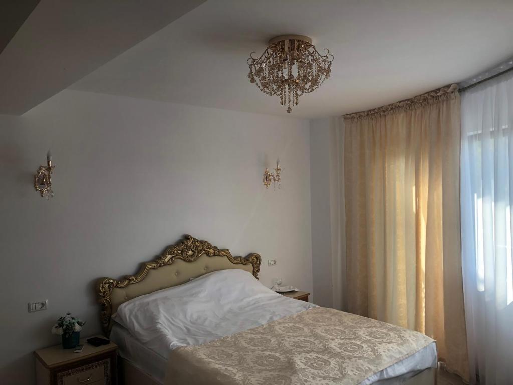 ein Schlafzimmer mit einem Bett und einem Kronleuchter in der Unterkunft FLORENA HOUSE in Pecineaga