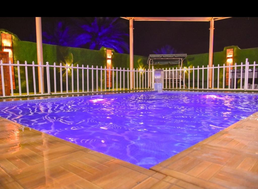 a purple swimming pool with a white fence at night at شالية البندرvip in Ḩifrī