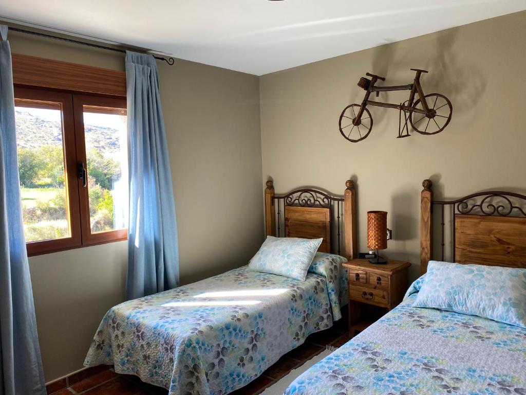 アビラにあるCasa Rural El Corralのベッドルーム1室(ベッド2台付)、壁に自転車1台が備わります。
