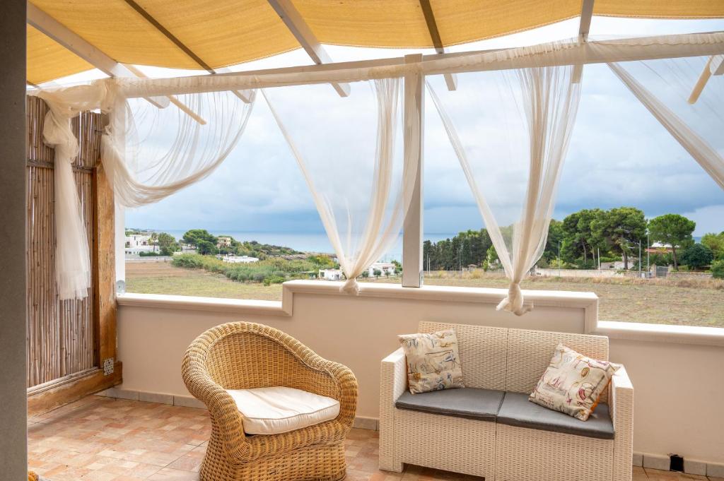 eine abgeschirmte Veranda mit einem Sofa und Stühlen vor einem Fenster in der Unterkunft A casa di Pietro Due in Leporano