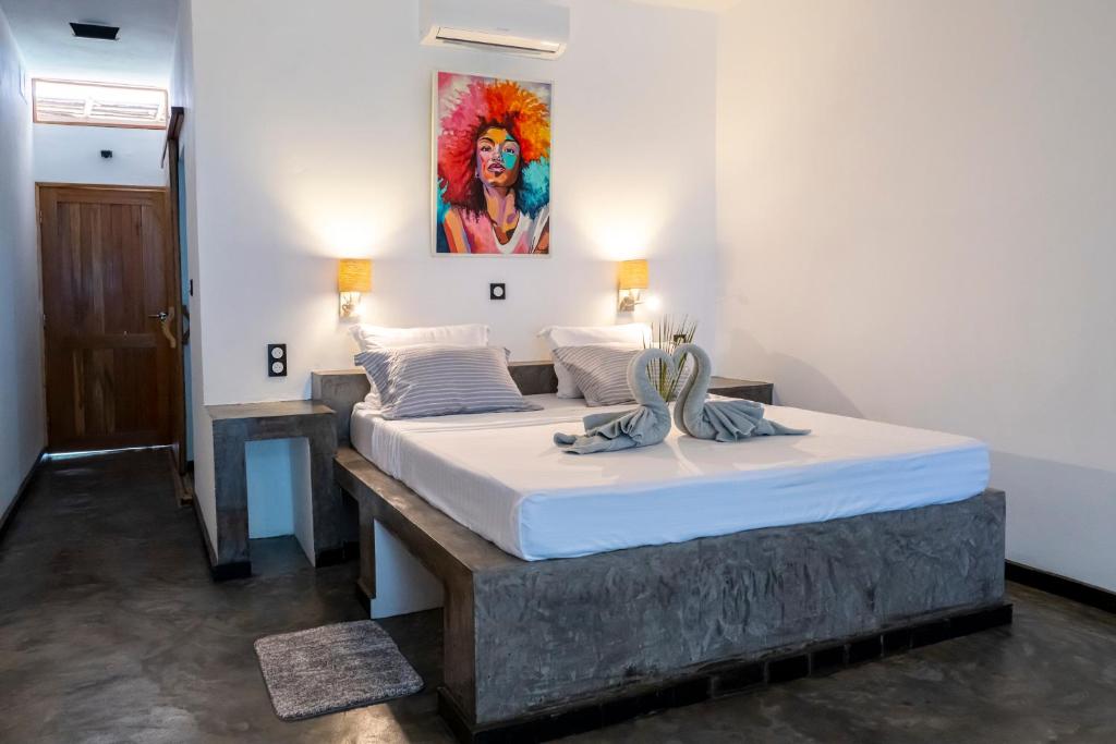 a bedroom with two beds and a painting on the wall at Swisscocobeach in Nosy Be