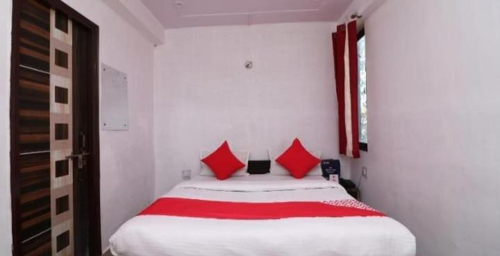 a bedroom with a large white bed with red pillows at Ganga Guest House By WB Inn in Agra
