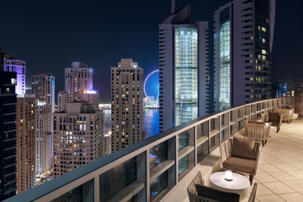 a balcony with chairs and a city skyline at night at InterContinental Dubai Marina by IHG in Dubai