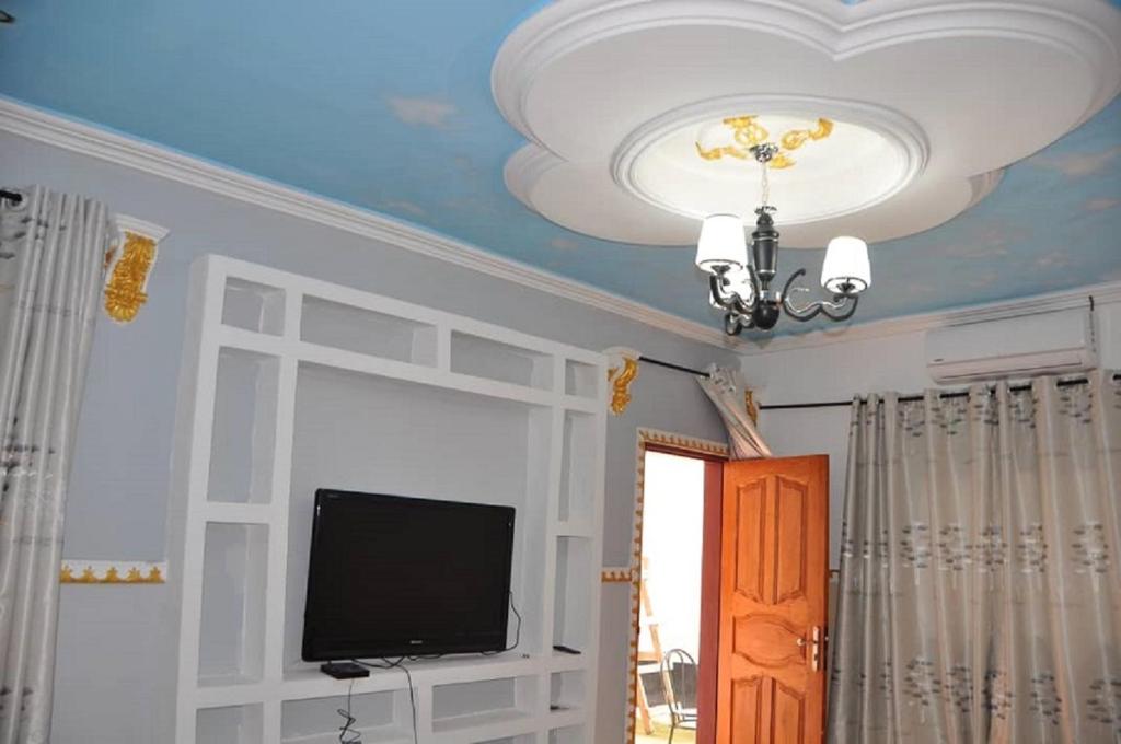 um quarto com um tecto, uma televisão e um lustre em Appartements meublés haut Standing em Bertoua