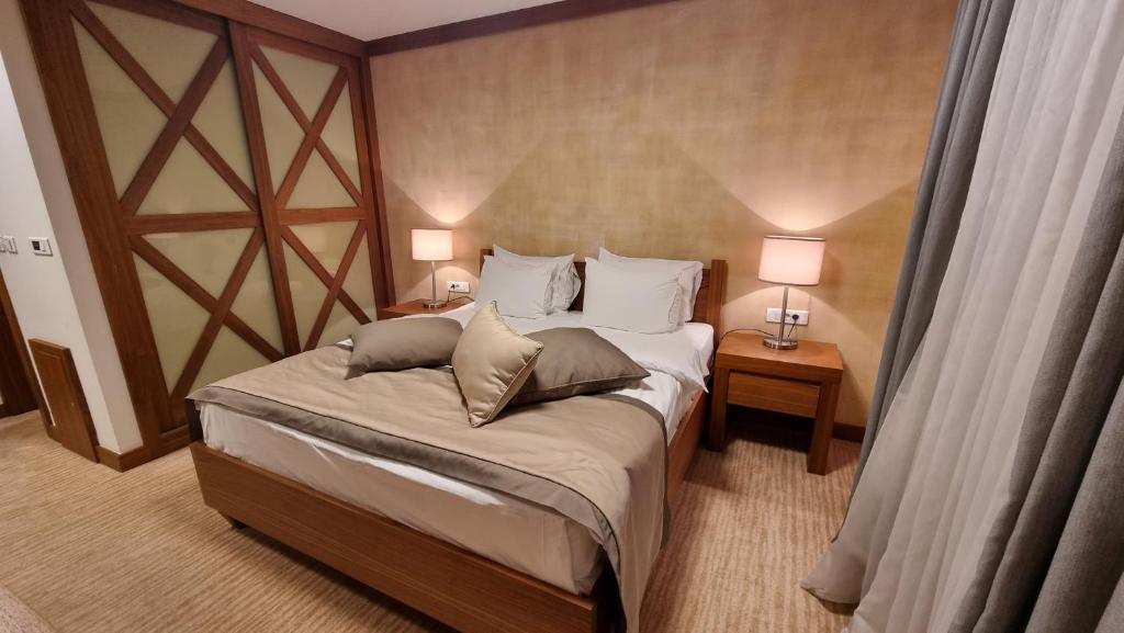 a bedroom with a large bed with two tables and two lamps at Apartman B428 Vucko private host in Jahorina