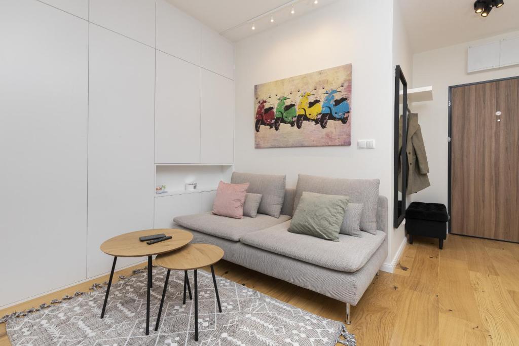 Gdańsk Vespa Apartment by Renters في غدانسك: غرفة معيشة مع أريكة وطاولة