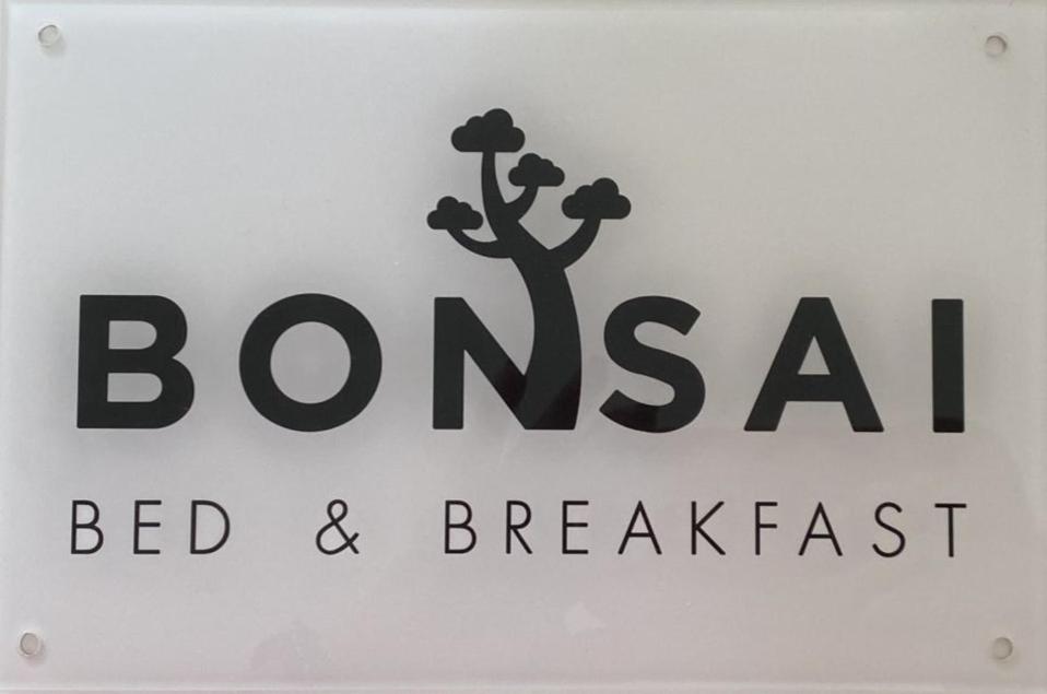 Bonsai - Bed & Breakfast في بيزارو: وضع علامة على السرير والافطار مع وجود شجرة عليه