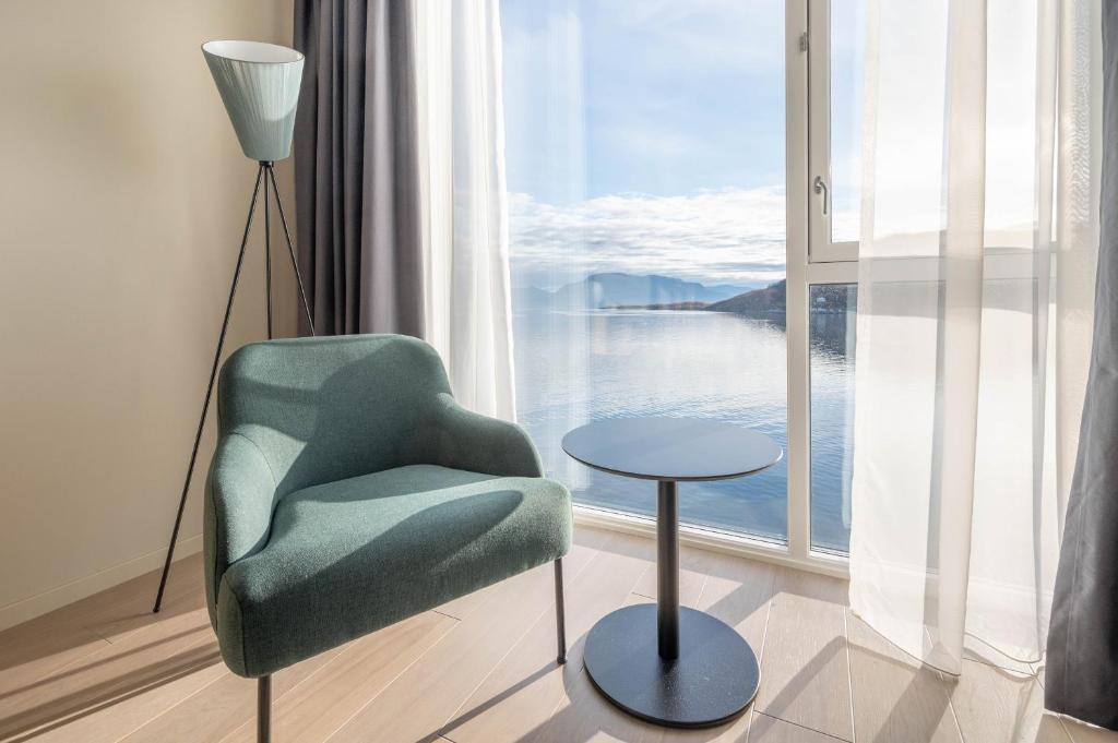 a room with a chair and a table and a window at Home Hotel Arcticus in Harstad