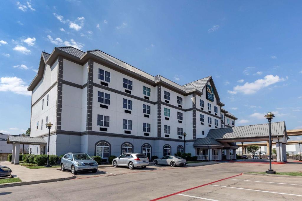 a large white building with cars parked in a parking lot at Quality Inn & Suites I-35 E-Walnut Hill in Dallas