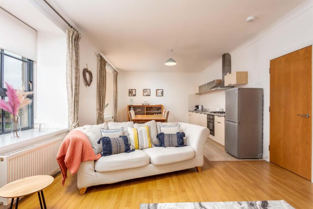 a living room with a white couch and a kitchen at No27 The Barclay - Donnini Apartments in Kilmarnock