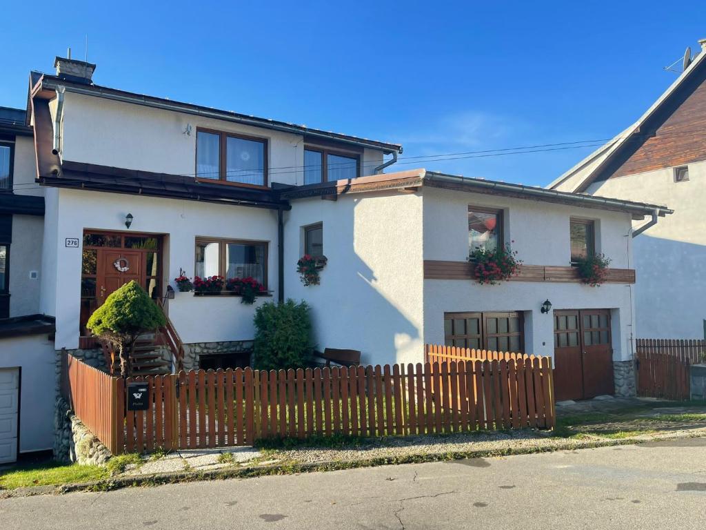 a white house with a wooden fence in front of it at Sifra 276 in Nová Lesná