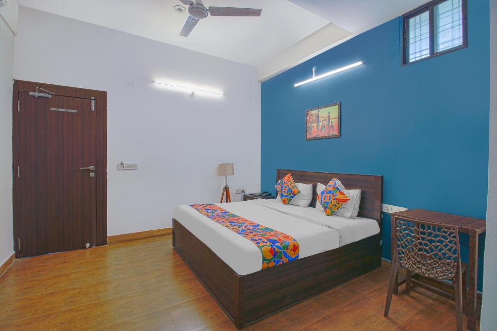 a bedroom with a bed and a blue wall at FabExpress Saket Inn in Bhopal
