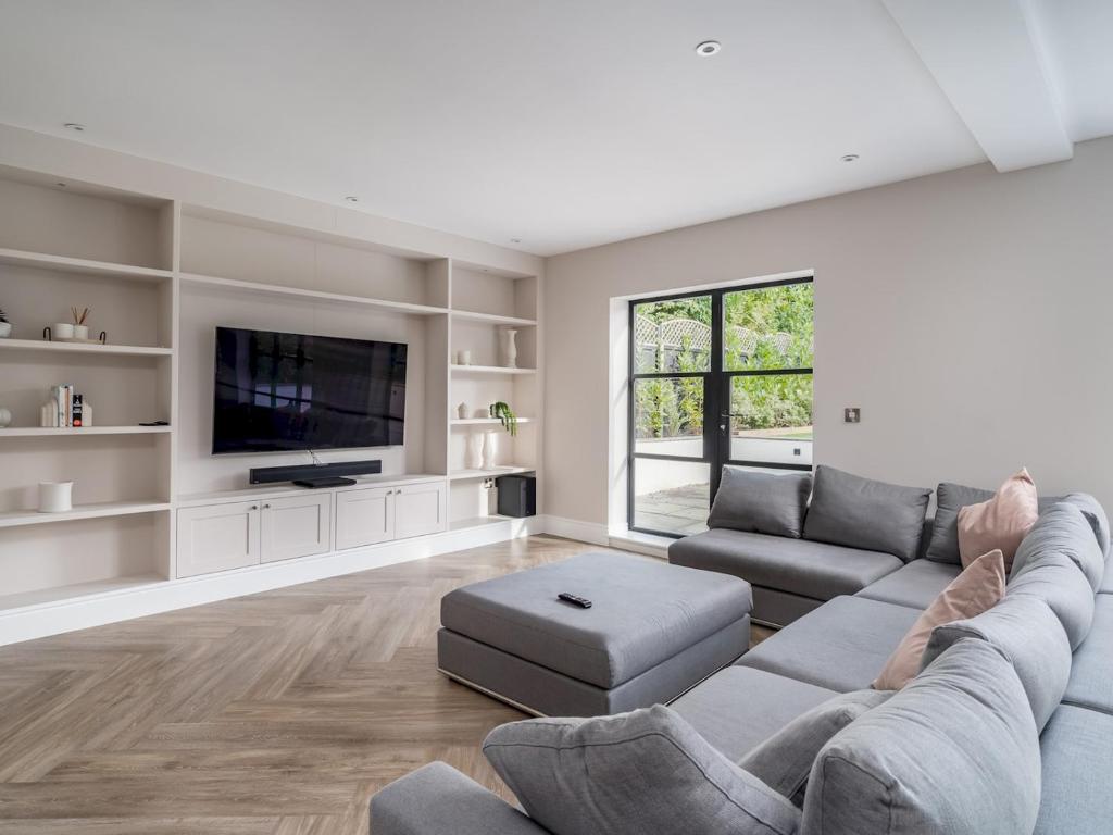 ein Wohnzimmer mit einem Sofa und einem TV in der Unterkunft Pass the Keys Luxury 4 Bedroom home with large garden in Watford
