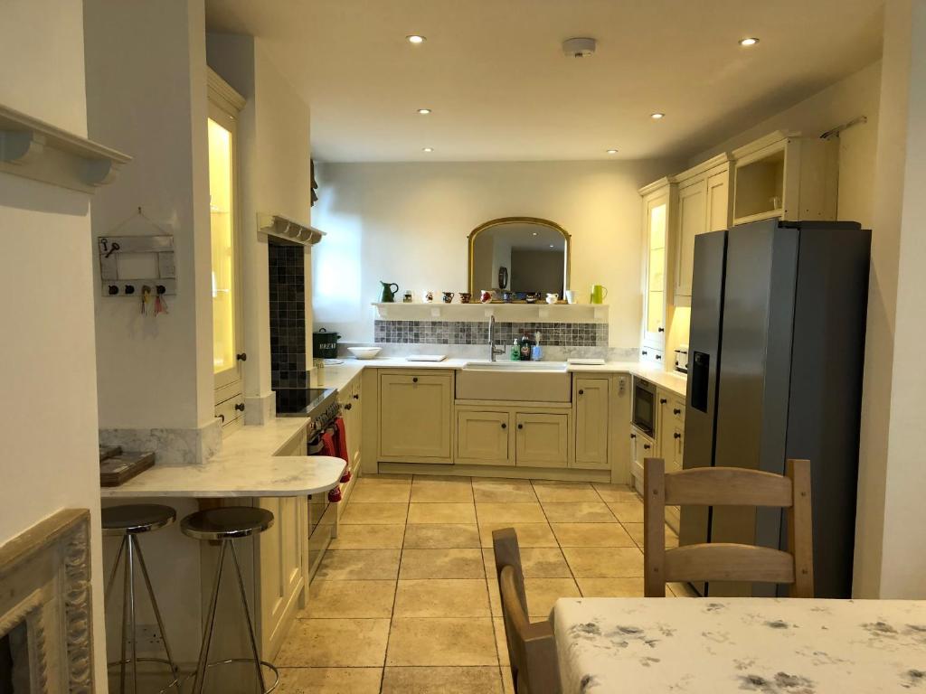 een keuken met een zwarte koelkast en een tafel bij Lauras Townhouse Apartments Lansdown Slope Townhouse in Bath
