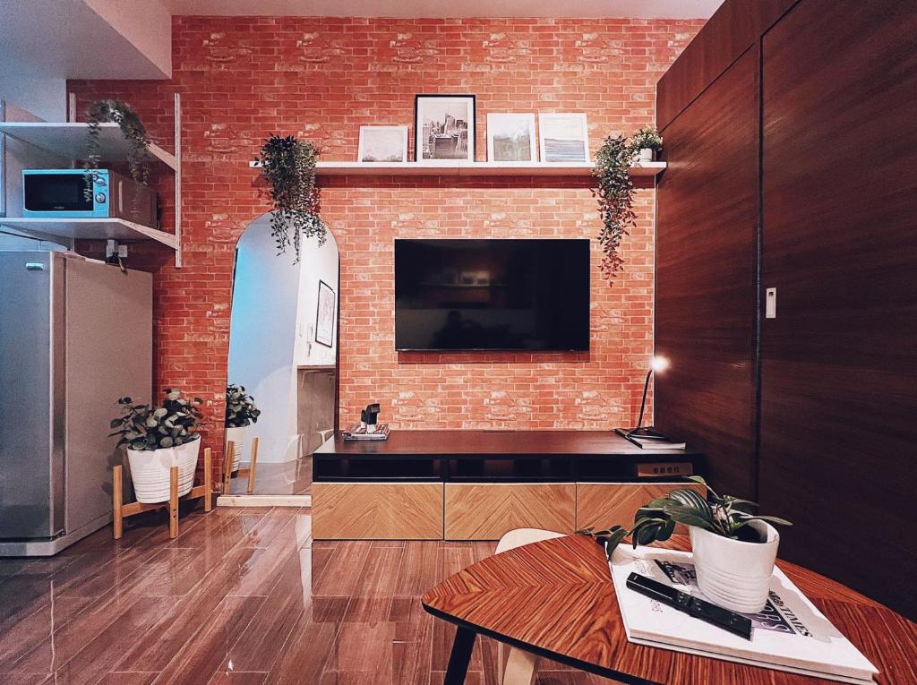 a living room with a brick wall with a tv at Makati Cosy Home l Couples Families l 500Mbps Wifi in Manila