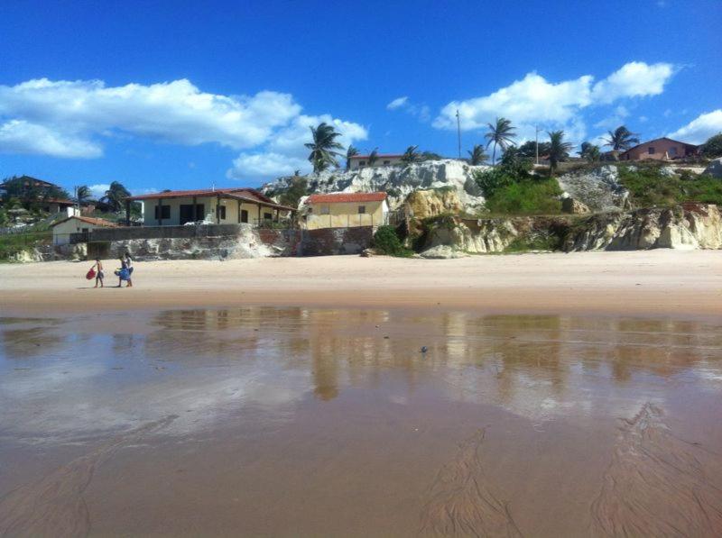 a beach with people walking on the sand and houses at Beach Place Fontainha in Aracati