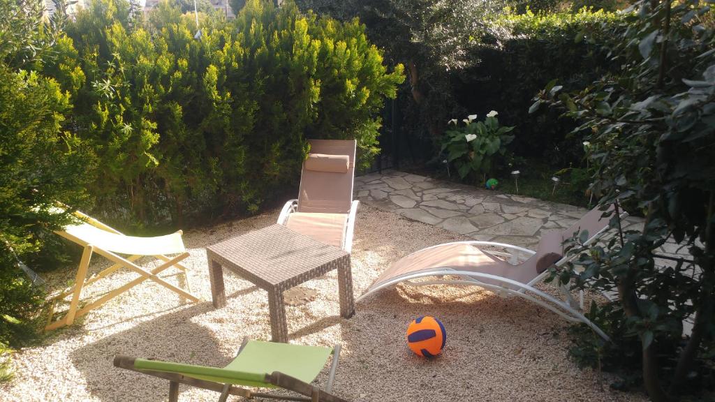 een achtertuin met stoelen en een tafel en stoelen bij Agréable T3 avec jardin et parking privé, à 350m du centre ville et des plages, wifi, remise supplémentaire de 10 pourcent pour une location à la semaine in Cavalaire-sur-Mer