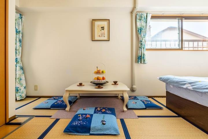 東京にある都心の家-ダブルベットと畳み3人部屋のテーブルと青いマットが備わる客室です。