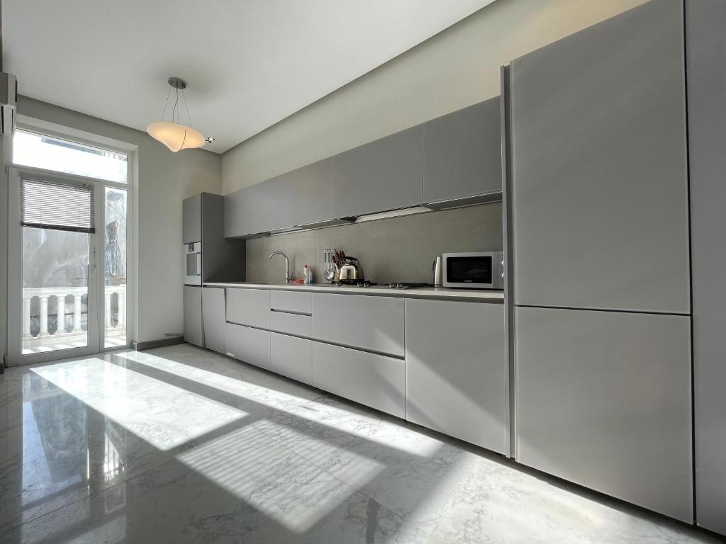 a kitchen with gray cabinets and a large window at Central Park apartment in Baku
