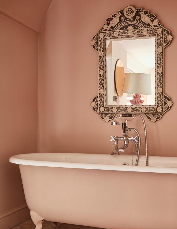a bathtub in a bathroom with a mirror at The George In Rye in Rye