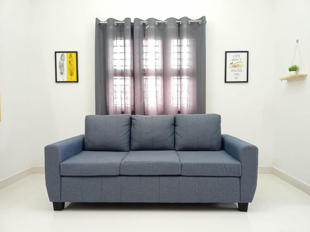 niebieską kanapę w salonie z oknem w obiekcie Meadows Homestay w mieście Maduraj