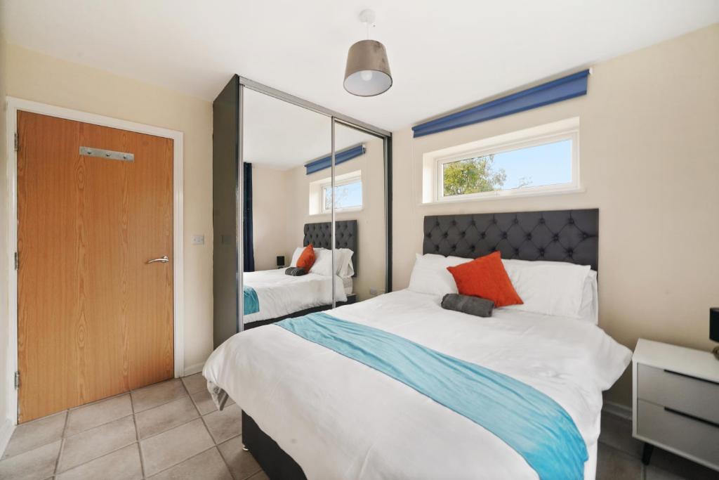 a bedroom with a large bed and a mirror at Spacious Modern Flat with Free Parking by Xenox Property Group in Stoke on Trent