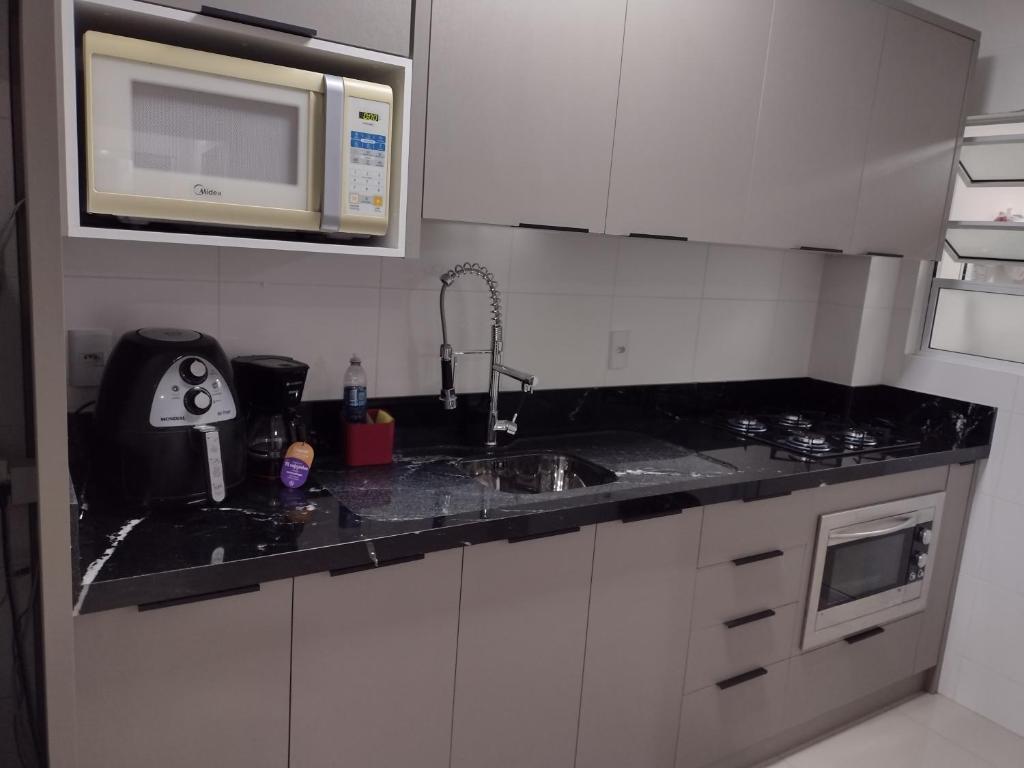 cocina con fregadero y microondas en Apartamento Praia de Palmas en Governador Celso Ramos
