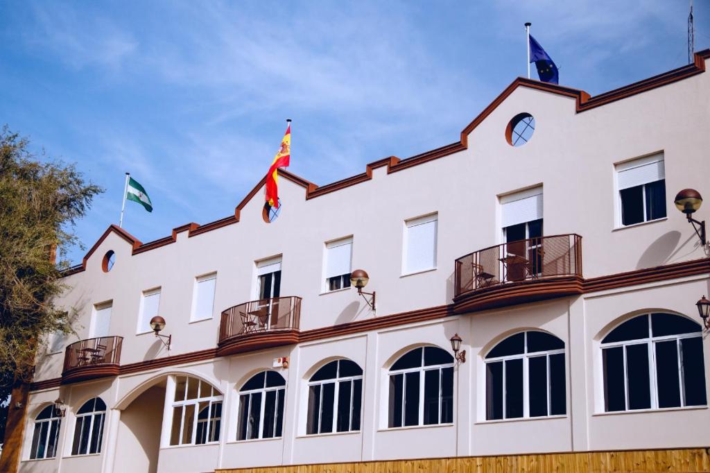 a building with three flags on top of it at Hotel Olive in Osuna